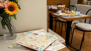 Una mesa de comedor con un mapa, un florero con flores y alimentos para el desayuno.