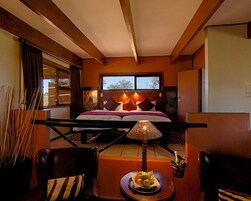 Un dormitorio con una cama, una mesita de noche, una lámpara, una silla y una mesa con fruta.