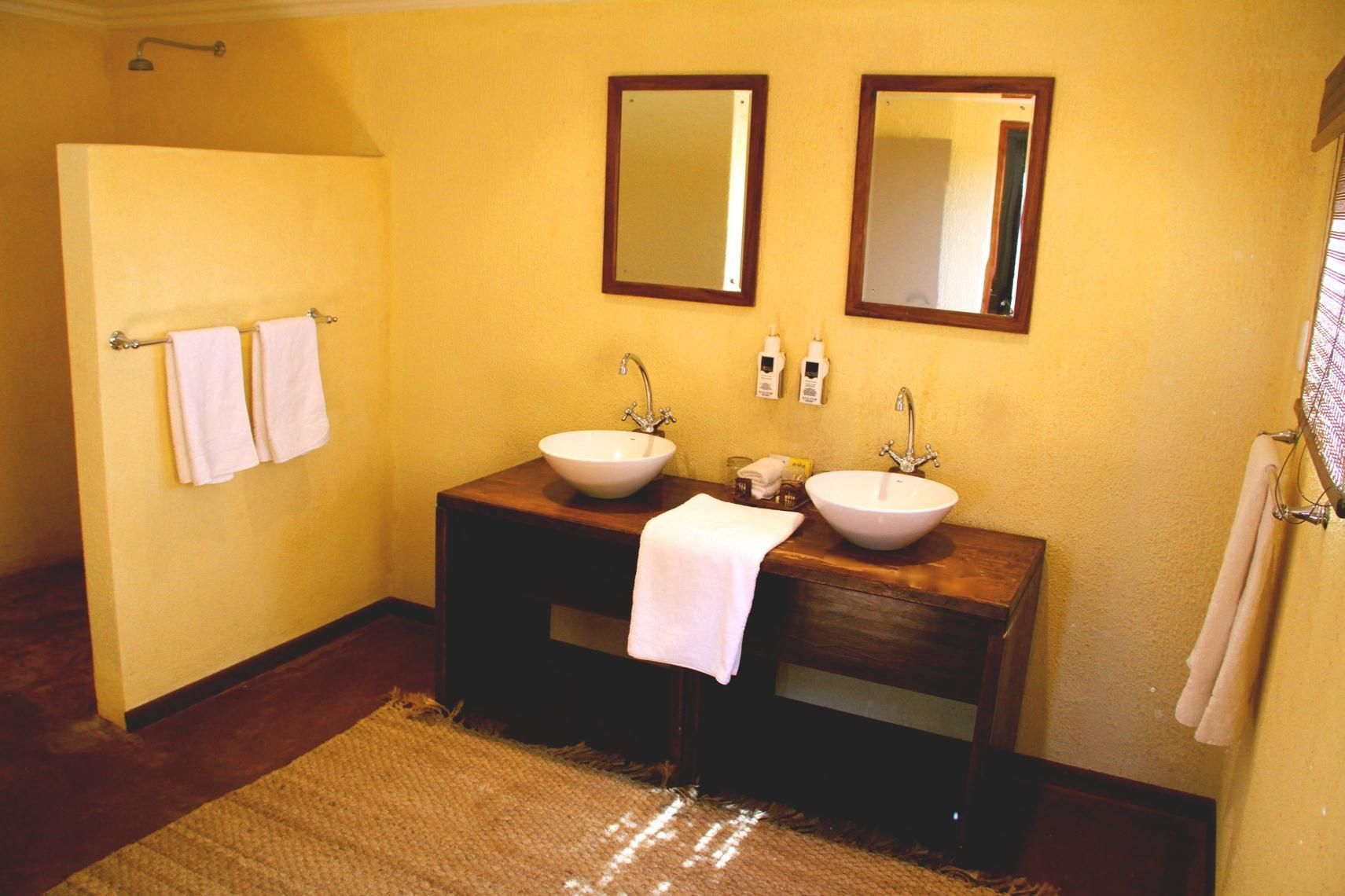 Un baño con dos lavamanos, un mueble de tocador de madera y dos espejos.