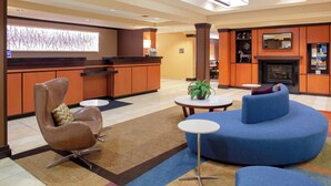 A hotel lobby with a reception desk, seating area, and a fireplace.
