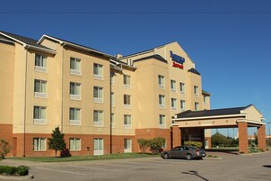 Un hotel de varios pisos con techo plano, entrada cubierta y estacionamiento con un automóvil.