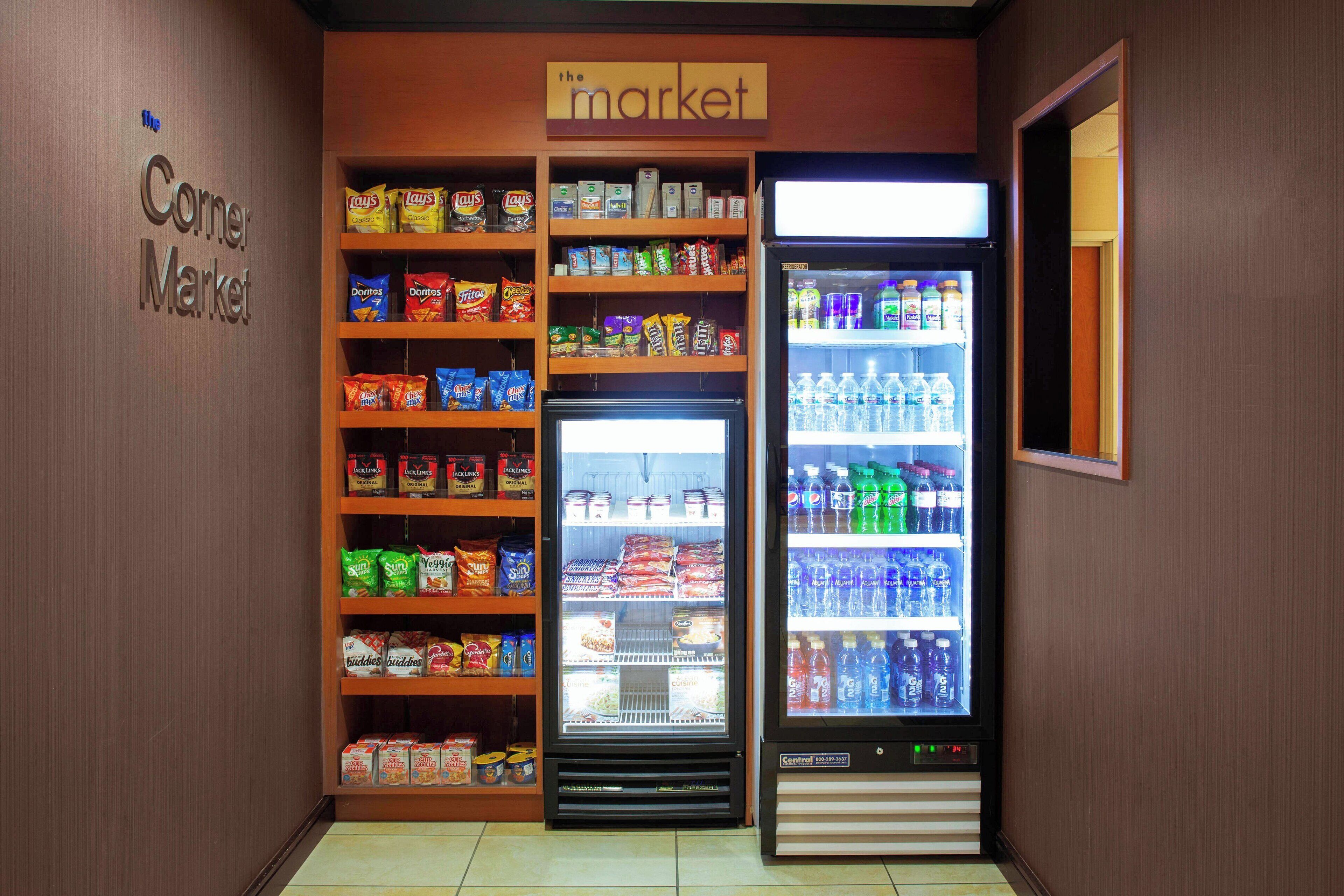 A corner market with shelves stocked with snacks and a refrigerated display.