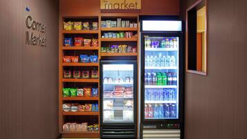 A corner market with shelves stocked with snacks and a refrigerated display.