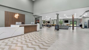 A spacious lobby with a reception desk, seating area, and a large window providing natural light. - Holiday Inn Oklahoma City Airport by IHG (Oklahoma City)