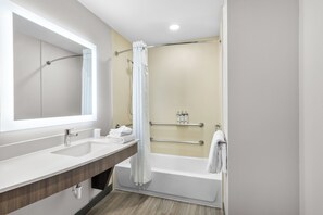 A modern bathroom with a double sink vanity, a bathtub, and a shower curtain. - Holiday Inn Oklahoma City Airport by IHG (Oklahoma City)