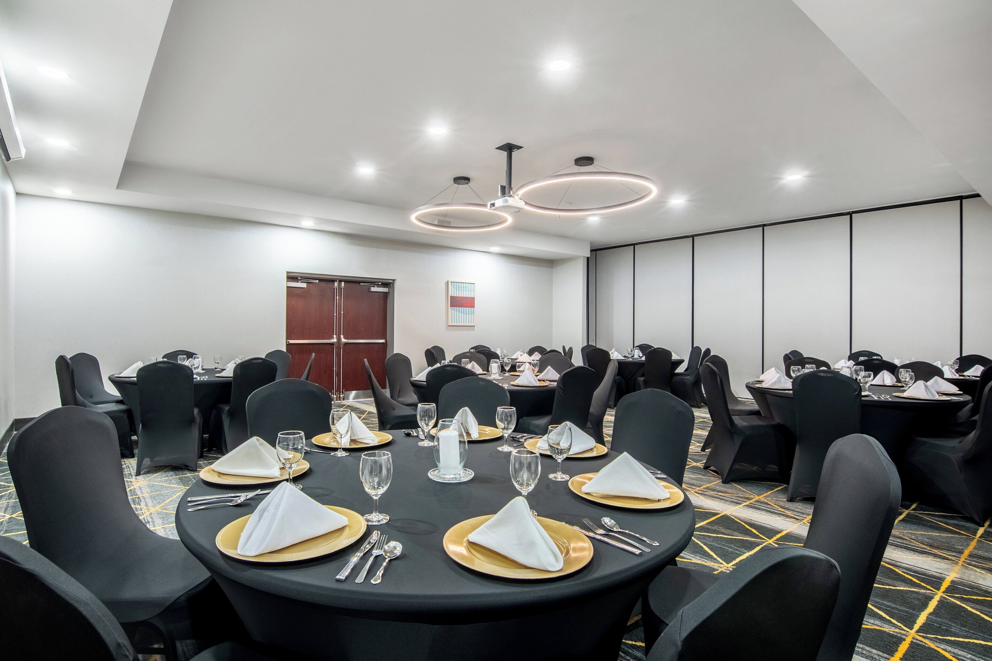 A conference room with round tables, black chairs, and a patterned carpet.