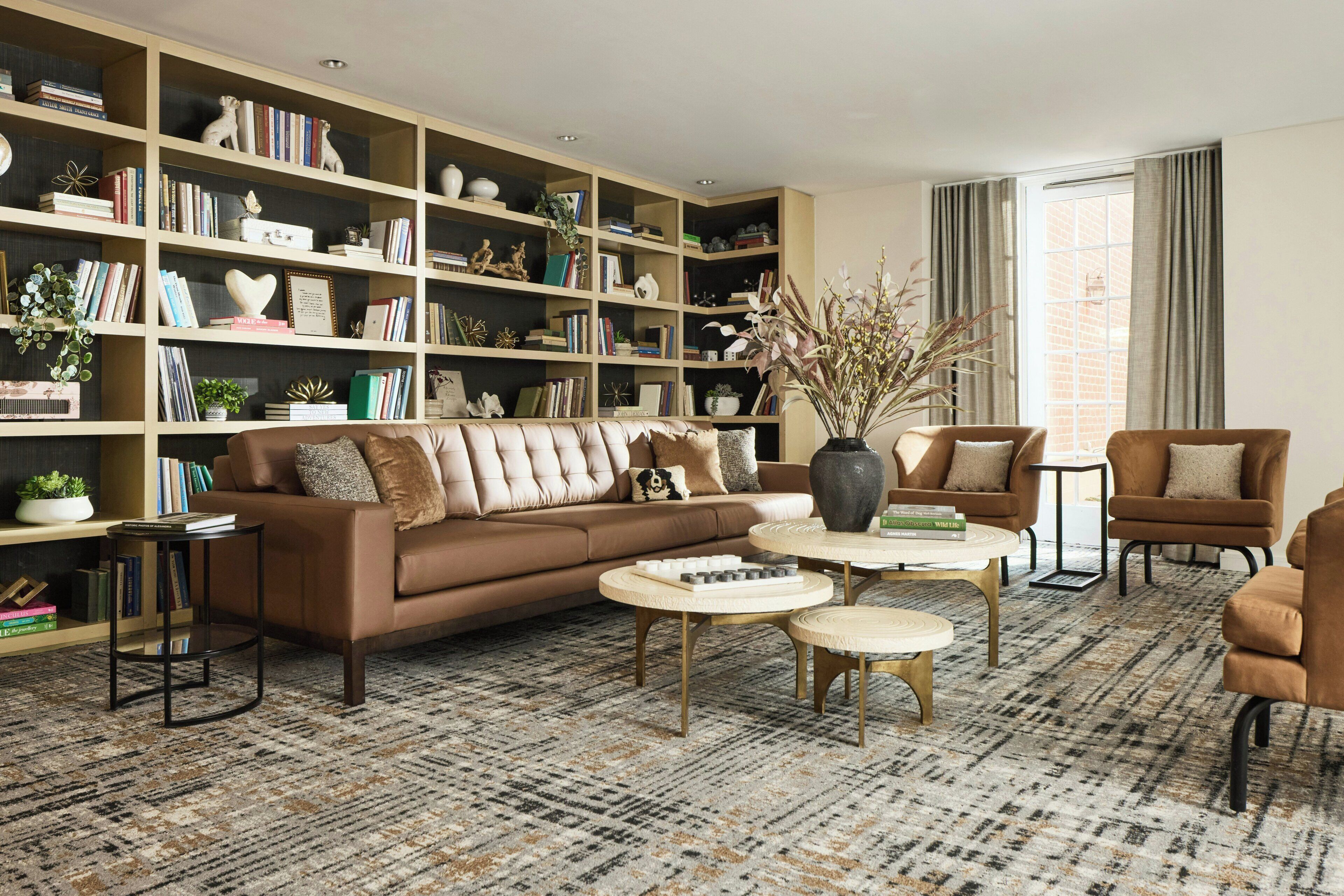 Un salon comprenant un canapé, des fauteuils, une table basse et une bibliothèque remplie de livres et d’objets décoratifs.