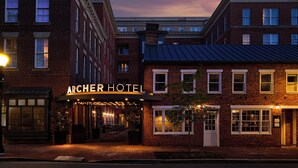 Un bâtiment en briques sur lequel on peut lire l’inscription « ARCHER HOTEL », et une zone de sièges extérieure abritée.