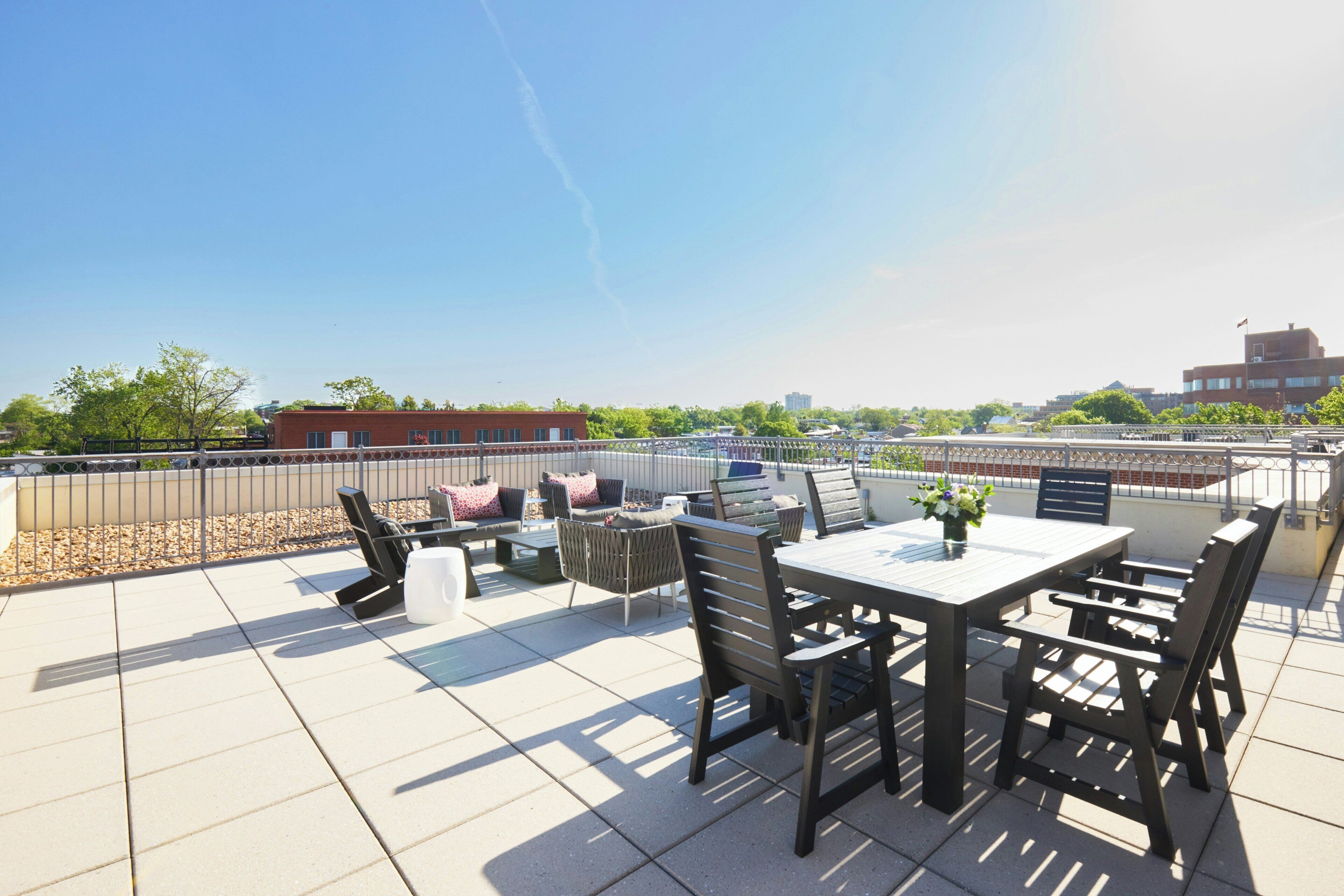 A rooftop terrace with a table and chairs, a small garden area, and a view of the cityscape.