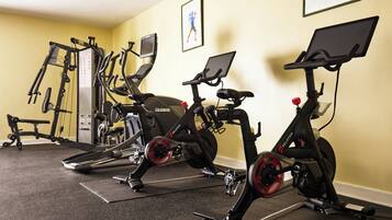 A gym with stationary bikes, a weight machine, and a treadmill.
