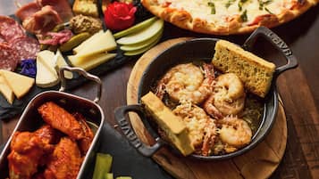 Une variété de produits alimentaires, notamment des crevettes, des ailes de poulet, du fromage et une pizza.
