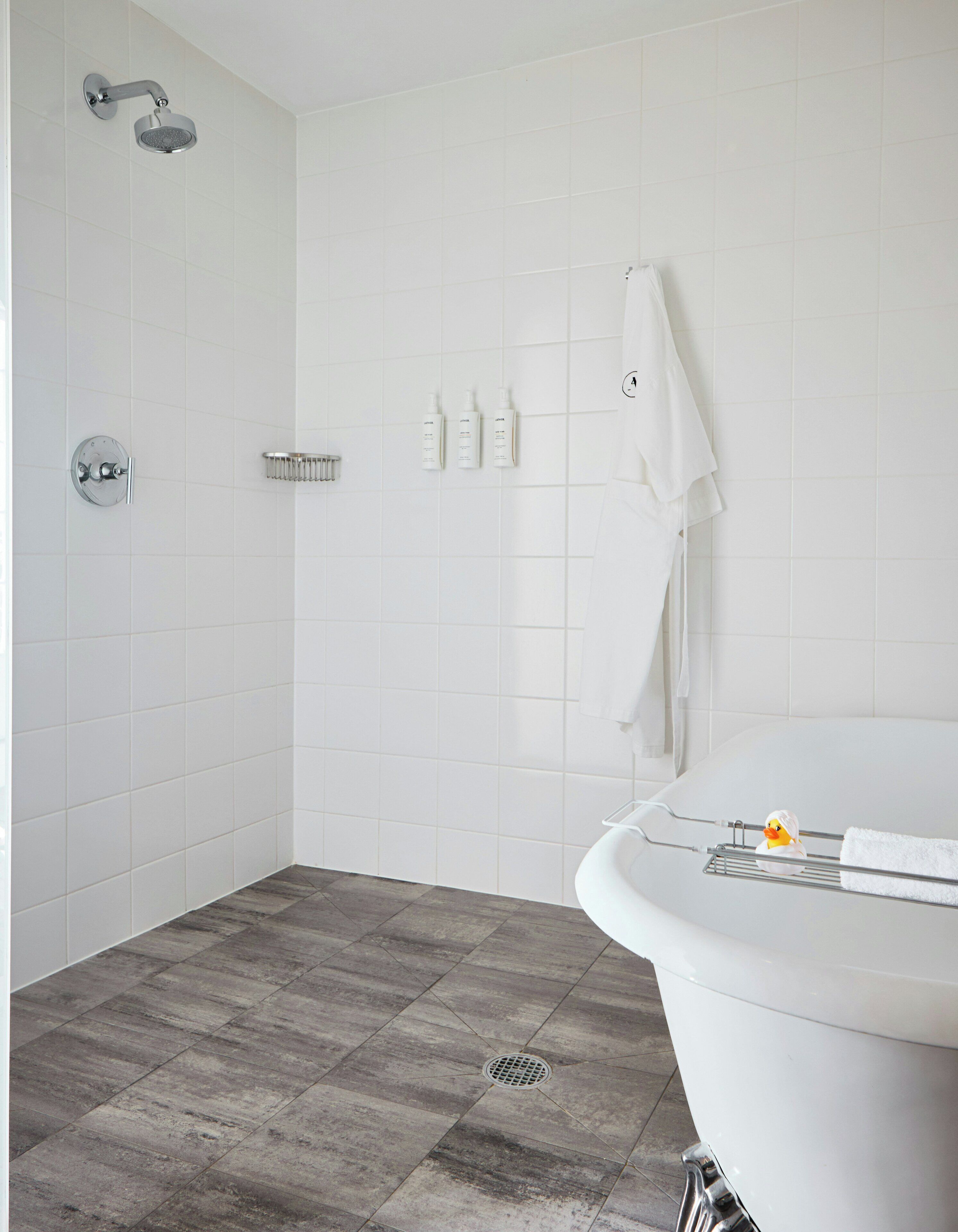 A bathroom with a shower, a bathtub, a white towel, and a rubber duck.