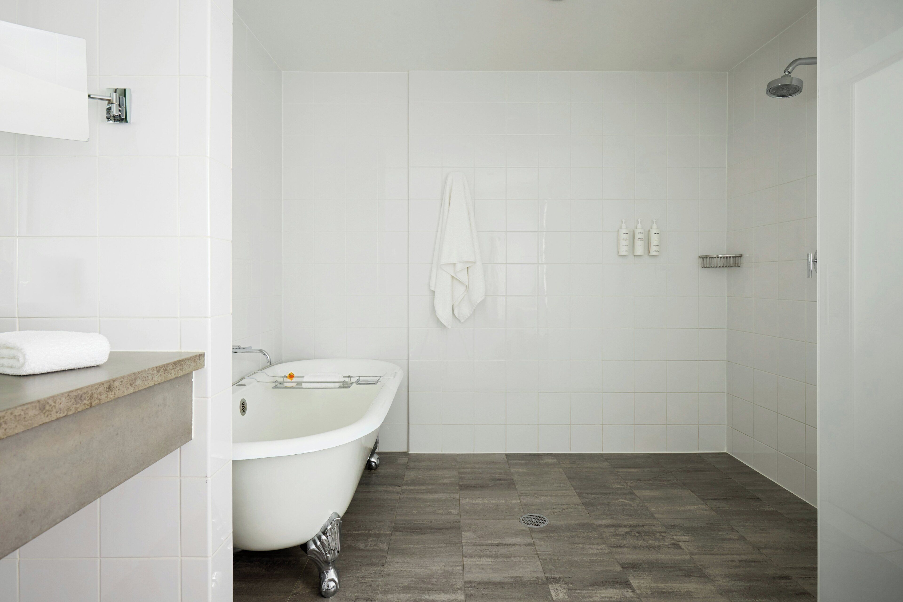 Un bagno moderno con una vasca freestanding, una doccia e un mobile lavabo con asciugamano.