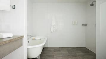 Un bagno moderno con una vasca freestanding, una doccia e un mobile lavabo con asciugamano.