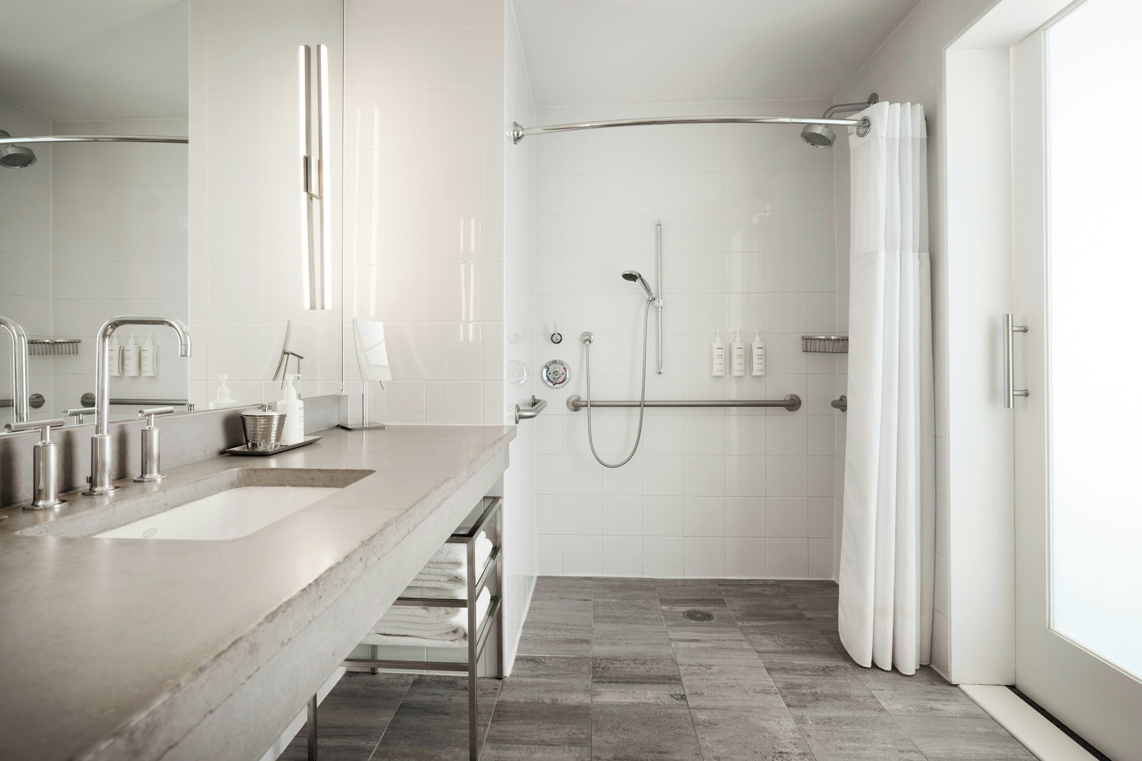 Un baño moderno con un lavamanos grande, una ducha con puerta de vidrio y un tocador con espejo.