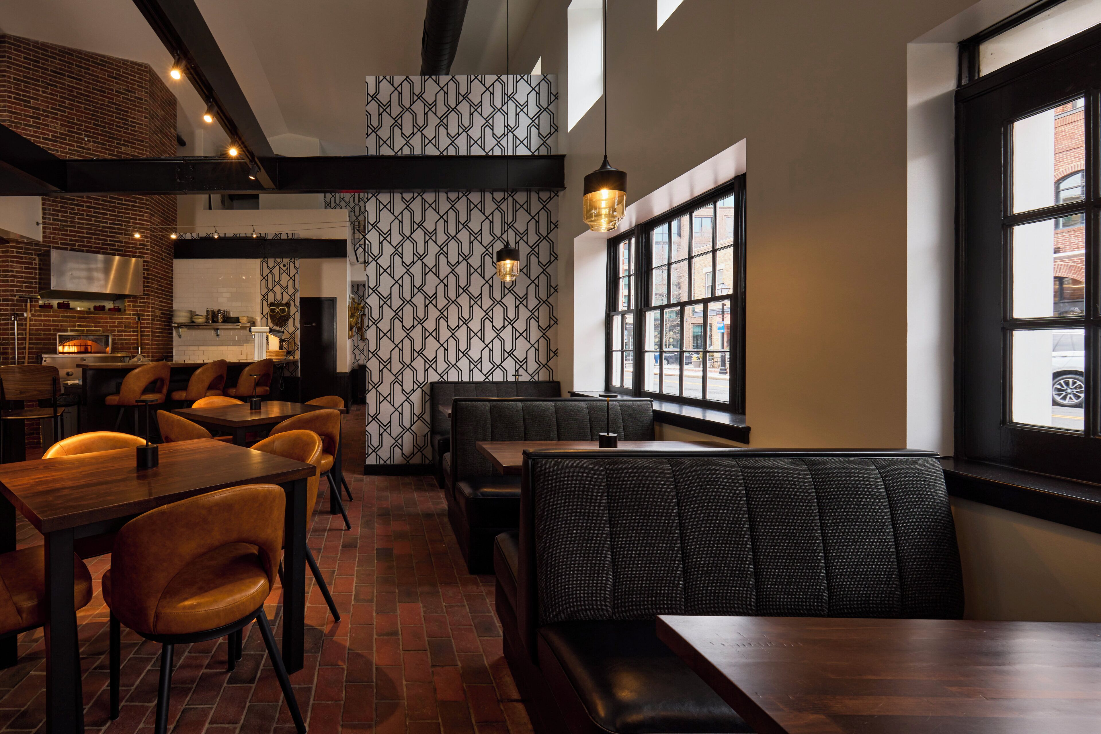 Un restaurante con paredes de ladrillo, papel tapiz estampado y una combinación de asientos de madera y tapizados.