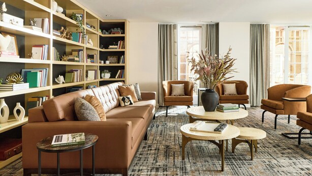 Un salon comprenant un canapé, des fauteuils, une table basse et une bibliothèque.