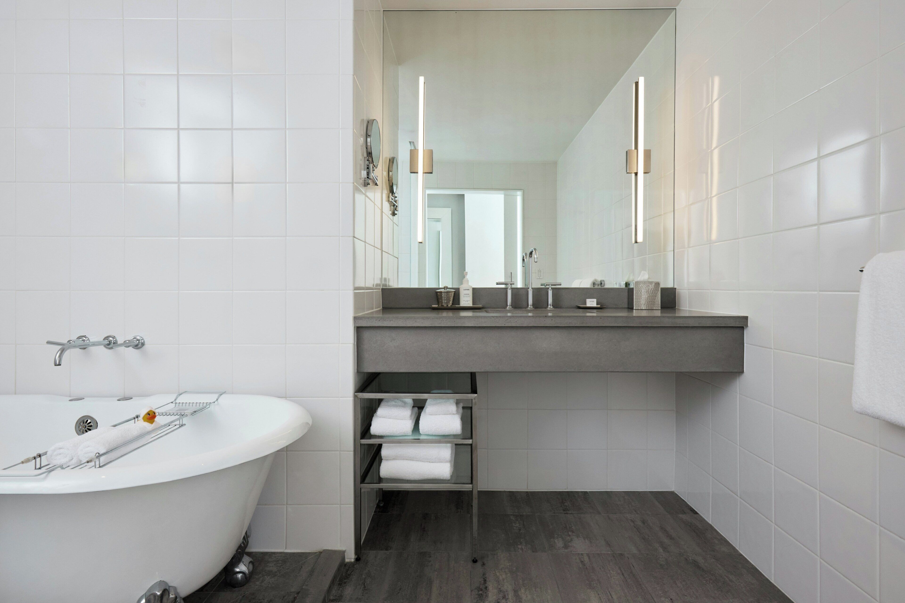 A modern bathroom with a freestanding bathtub, a vanity with a mirror, and a towel rack.