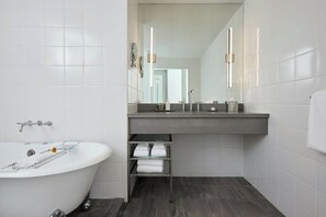 Une salle de bain moderne avec une baignoire sur pieds, un meuble-lavabo avec un miroir et un porte-serviettes.