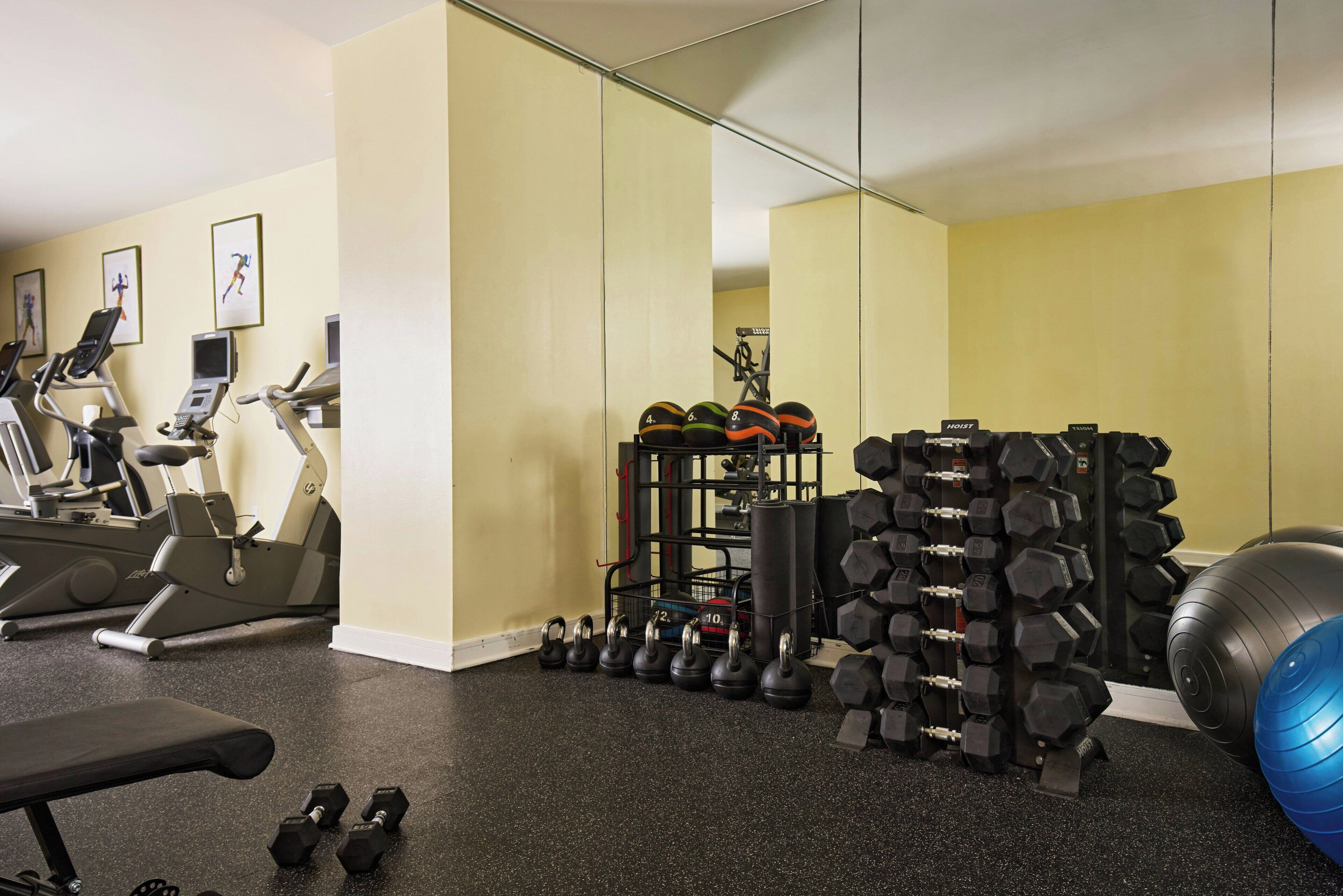 A gym with exercise equipment, a bench, and a mirror.