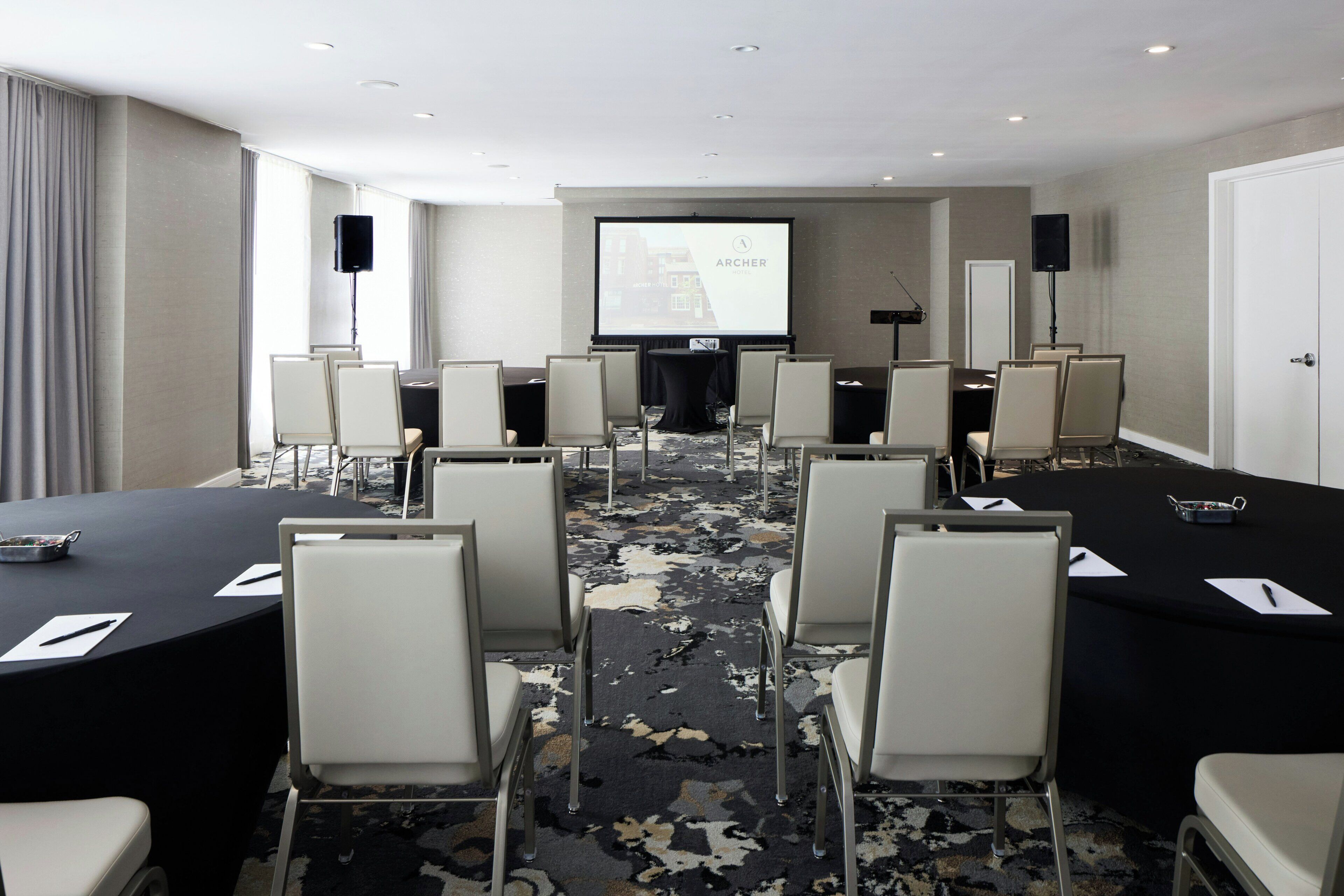 A conference room with a large screen, multiple chairs, and tables.