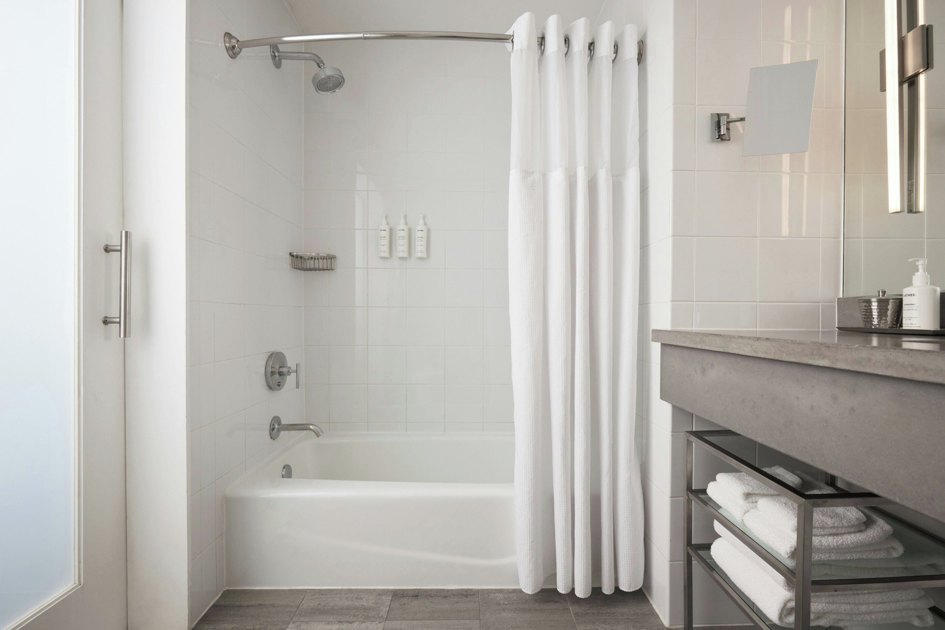 Un bagno moderno con doccia, ripiano in vetro con asciugamani e specchio.