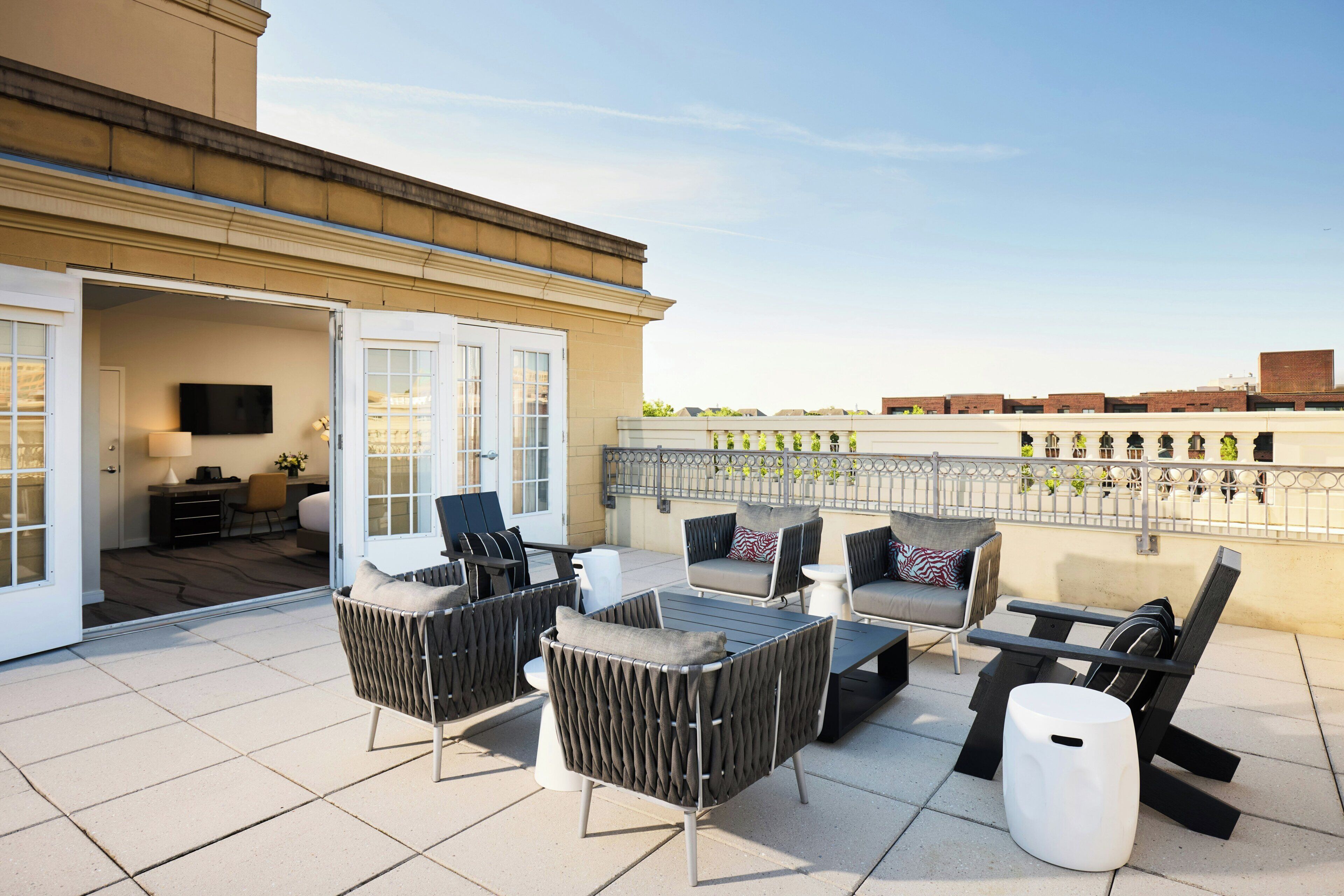 A rooftop terrace with outdoor furniture, a flat-screen TV, and a view of the cityscape.