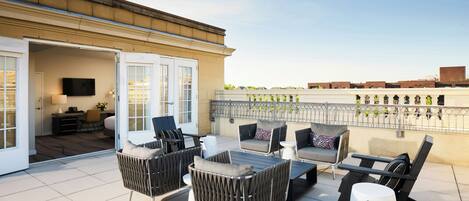 A rooftop terrace with outdoor furniture, a flat-screen TV, and a view of the cityscape.