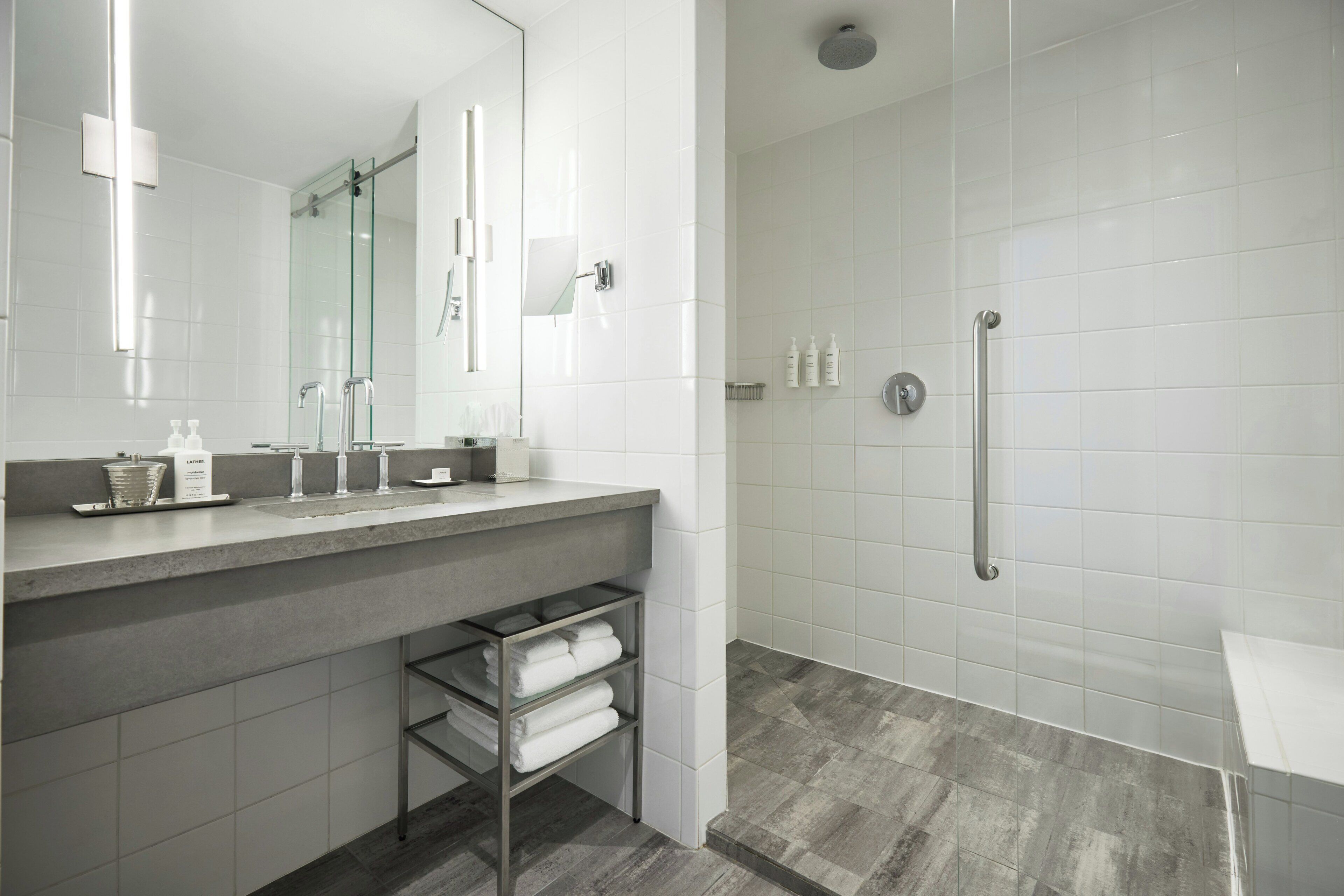 Un baño moderno con cabina de ducha de vidrio, tocador con espejo y un perchero para toallas.