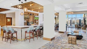 A modern bar area with a wooden ceiling, bar stools, and a television screen.
