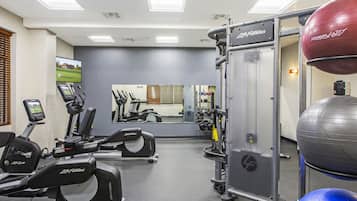 A gym with exercise equipment, a mirror, and a television.