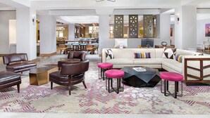 A spacious living area with a sofa set, leather chairs, a coffee table, and a patterned rug.