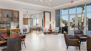 A spacious hotel lobby with a bar area, seating arrangements, and large windows offering views.