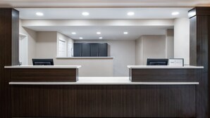 A reception desk with two counters, a dark wood finish, and a tiled floor.