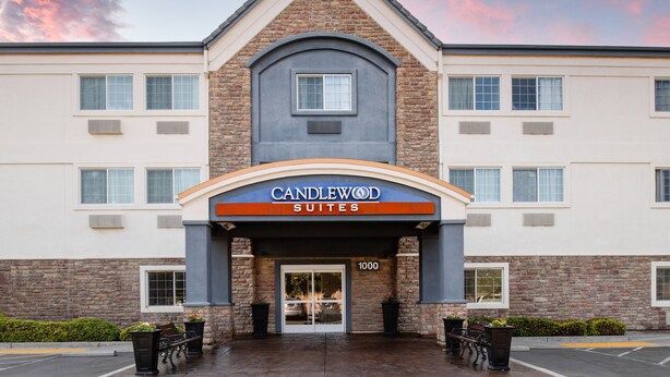 Entrada de un hotel con un cartel que dice "Candlewood Suites" y el número "1000" sobre la puerta.