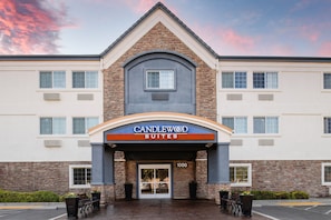 A hotel entrance with a sign reading "Candlewood Suites" and a number "1000" above the door.