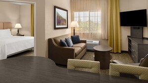 A hotel room with a bed, a sofa, a TV, and a desk.