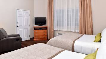 A hotel room with two beds, a television, a dresser, and a door.