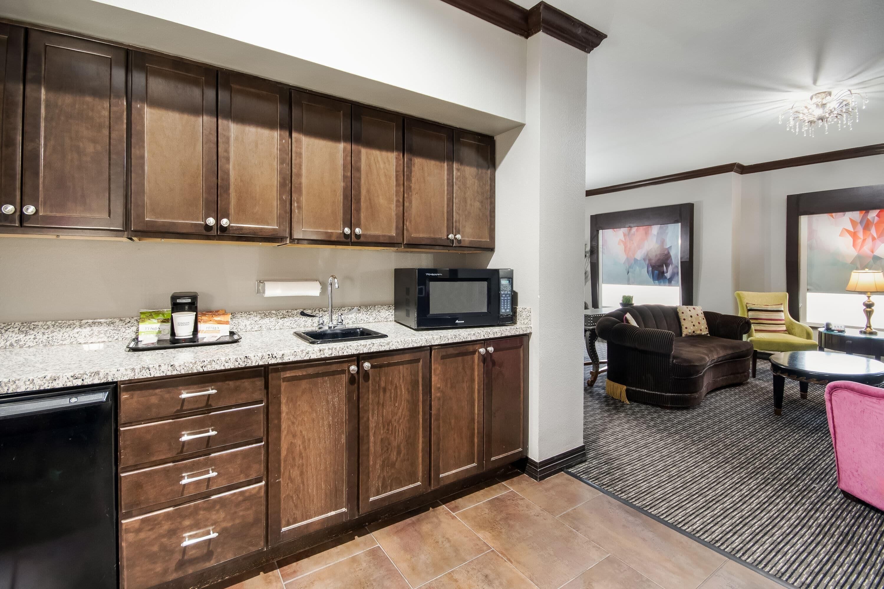 A modern kitchen with dark wooden cabinets, a granite countertop, and a built-in microwave.