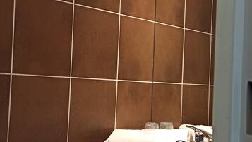 A bathroom with brown tiles, a white sink, and a mirror.