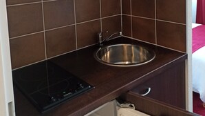 A compact kitchenette with a microwave, sink, and stove. - Résidence Hôtelière des Ondes (Saint-Lys)