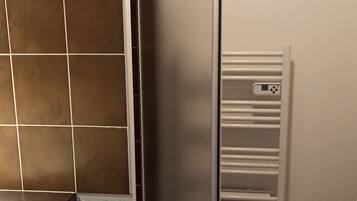 A bathroom with a toilet, a shower enclosure, and a sink area.