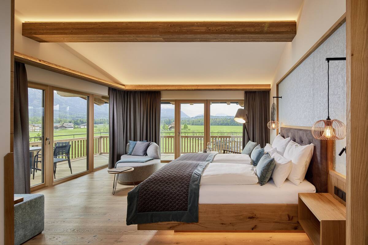 Un dormitorio amplio con una cama grande, un balcón y vistas al campo.