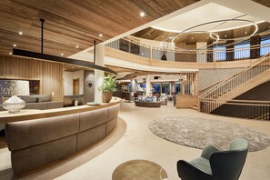 A spacious lobby with a curved reception desk, a staircase, and a large seating area. - Laschenskyhof Hotel & Spa (Wals-Siezenheim)