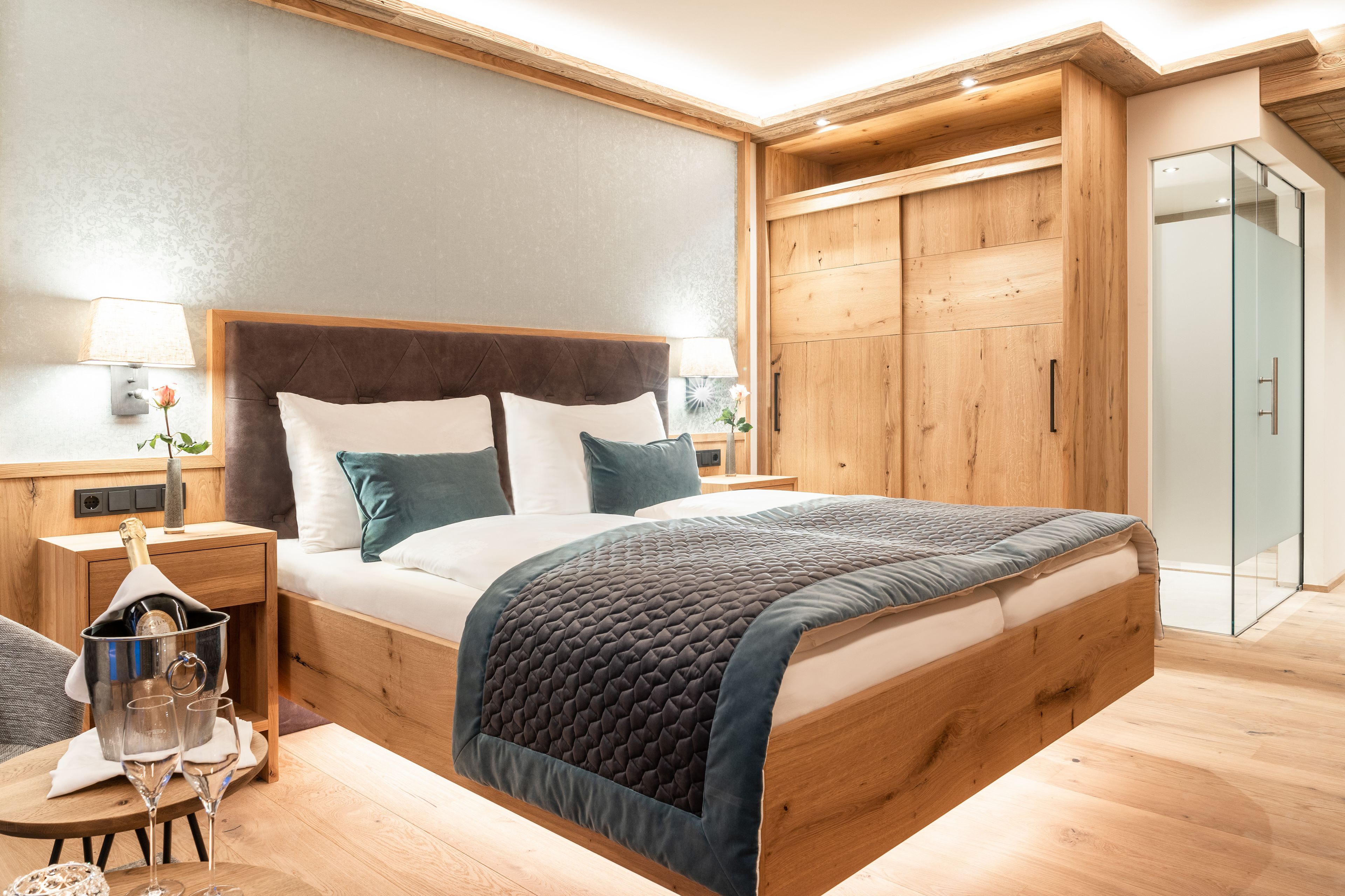 A modern bedroom with a wooden bed frame, a large window, and a wooden wardrobe.