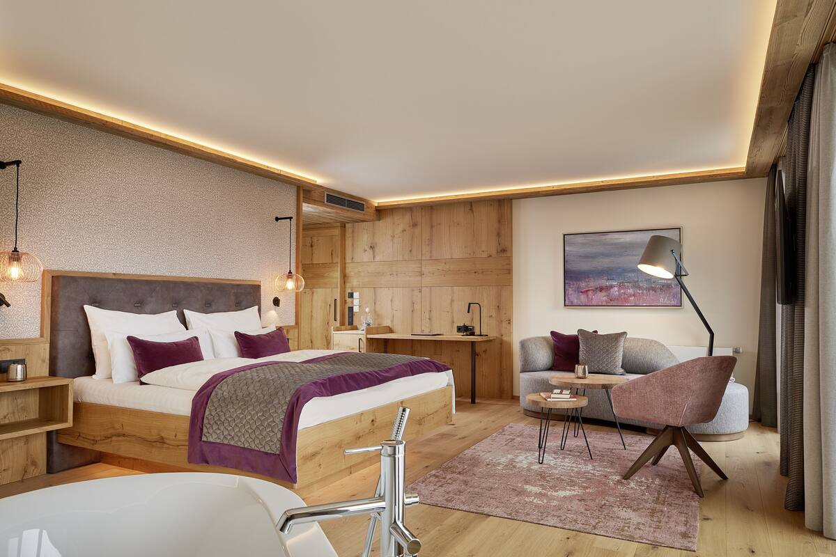 Un dormitorio moderno con cabecera de madera, una cama grande, un escritorio, una silla y un cuadro en la pared.