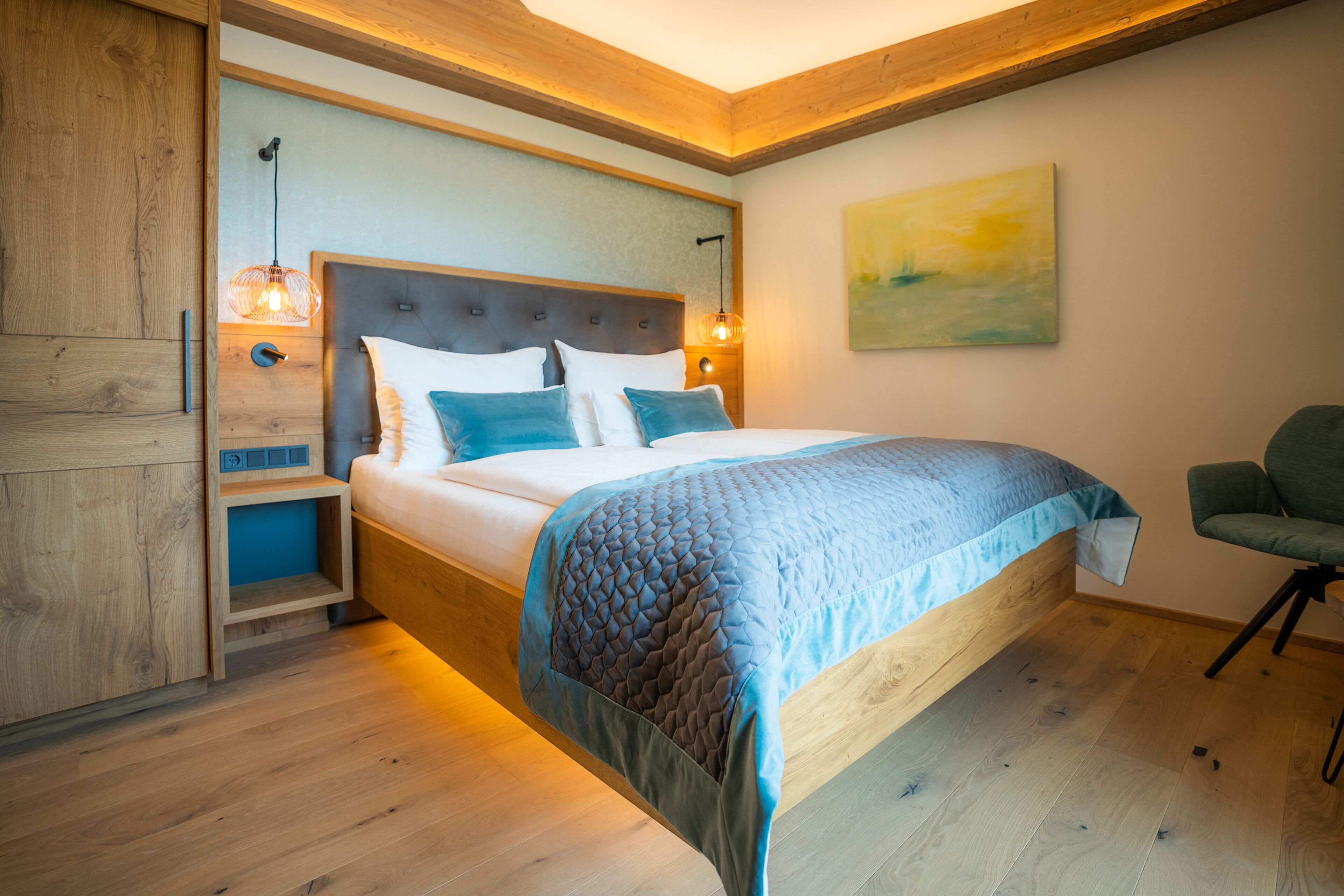 Ein Schlafzimmer mit einem hölzernen Bett, einem Nachttisch, einem Sessel und einem Bild an der Wand.