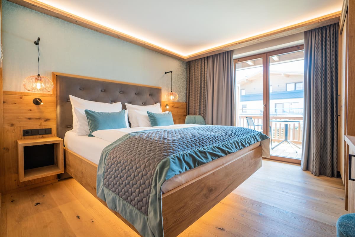Un dormitorio amplio con una cama grande, cabecera de madera y vistas al balcón.