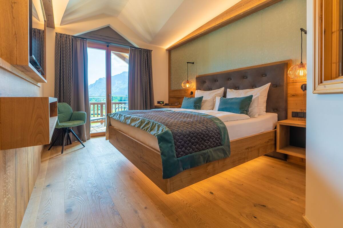 Un dormitorio con una cama grande, cabecera de madera y un balcón con vistas.