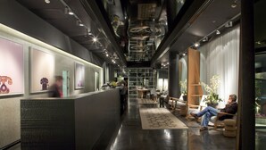 Un moderno vestíbulo de hotel con mostrador de recepción, zona de estar y una escalera que lleva a los pisos superiores.